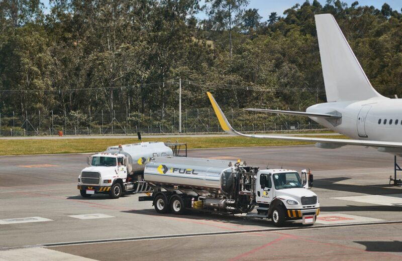 A picture of two trucks carrying jet fuel towards a private jet.